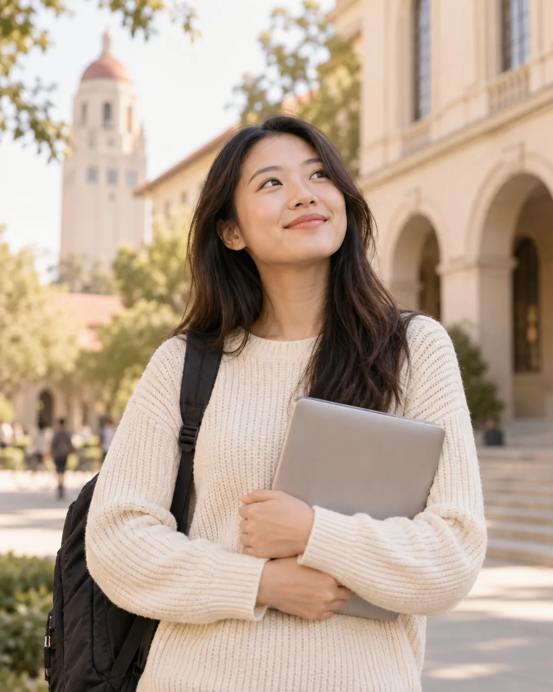 A university student holding a laptop on a sunlit campus.